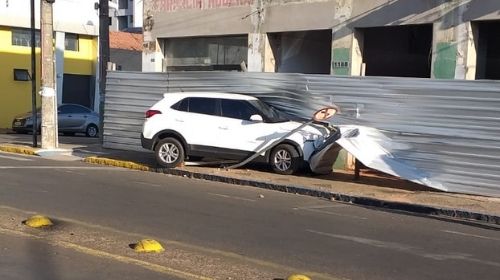 Caminhão cruza sinal vermelho e atinge veículo que vai parar em cima da calçada.