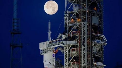 Imagem do nariz do foguete Artemis-i SLS, com a cápsula Orion, no pórtico de lançamento, à luz da Lua — Foto: GETTY IMAGES via BBC